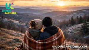 Young couple sharing one warm blanket while watching the sunset over winter hills